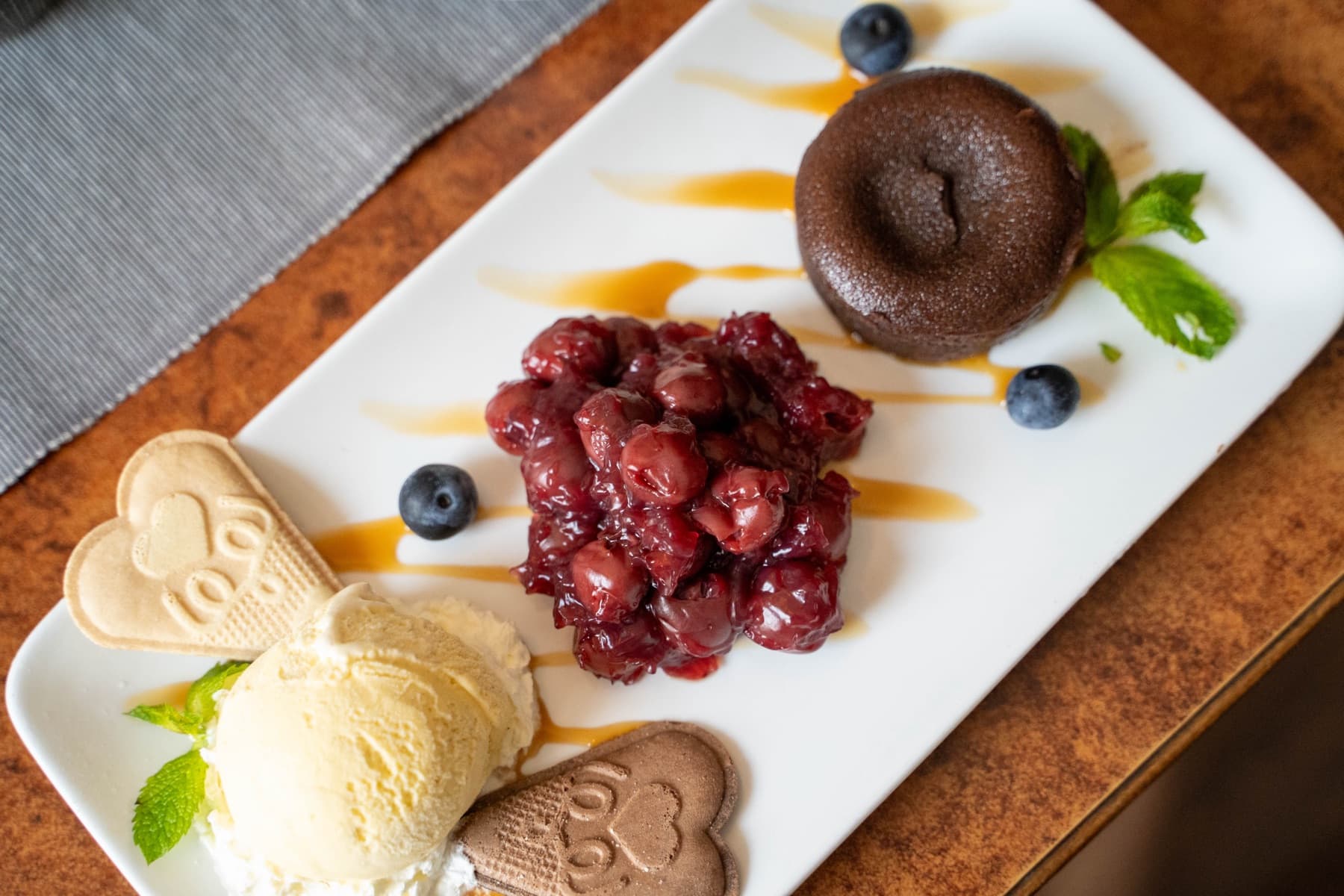 Angerichtetes Dessert mit Schokoladenküchlein, Kirschen und Vanilleeis auf langer Platte