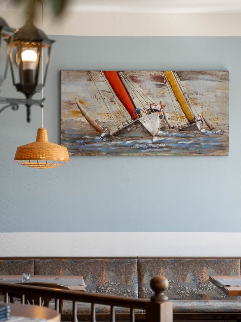 Gastraum des Restaurant Sulsdorf mit Segelbild an der Wand, alten Laternen und warmen Pendelleuchten