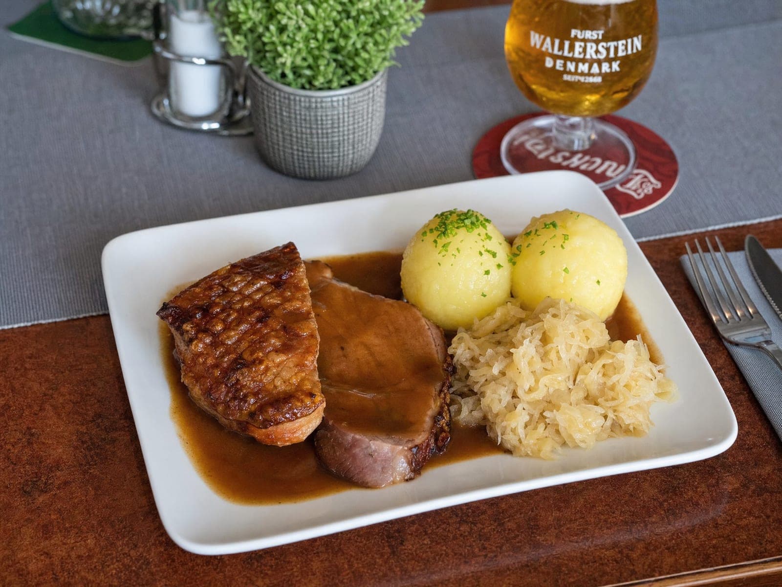 Krustenbraten mit zwei Kartoffelknödeln, Sauerkraut und dunkler Soße