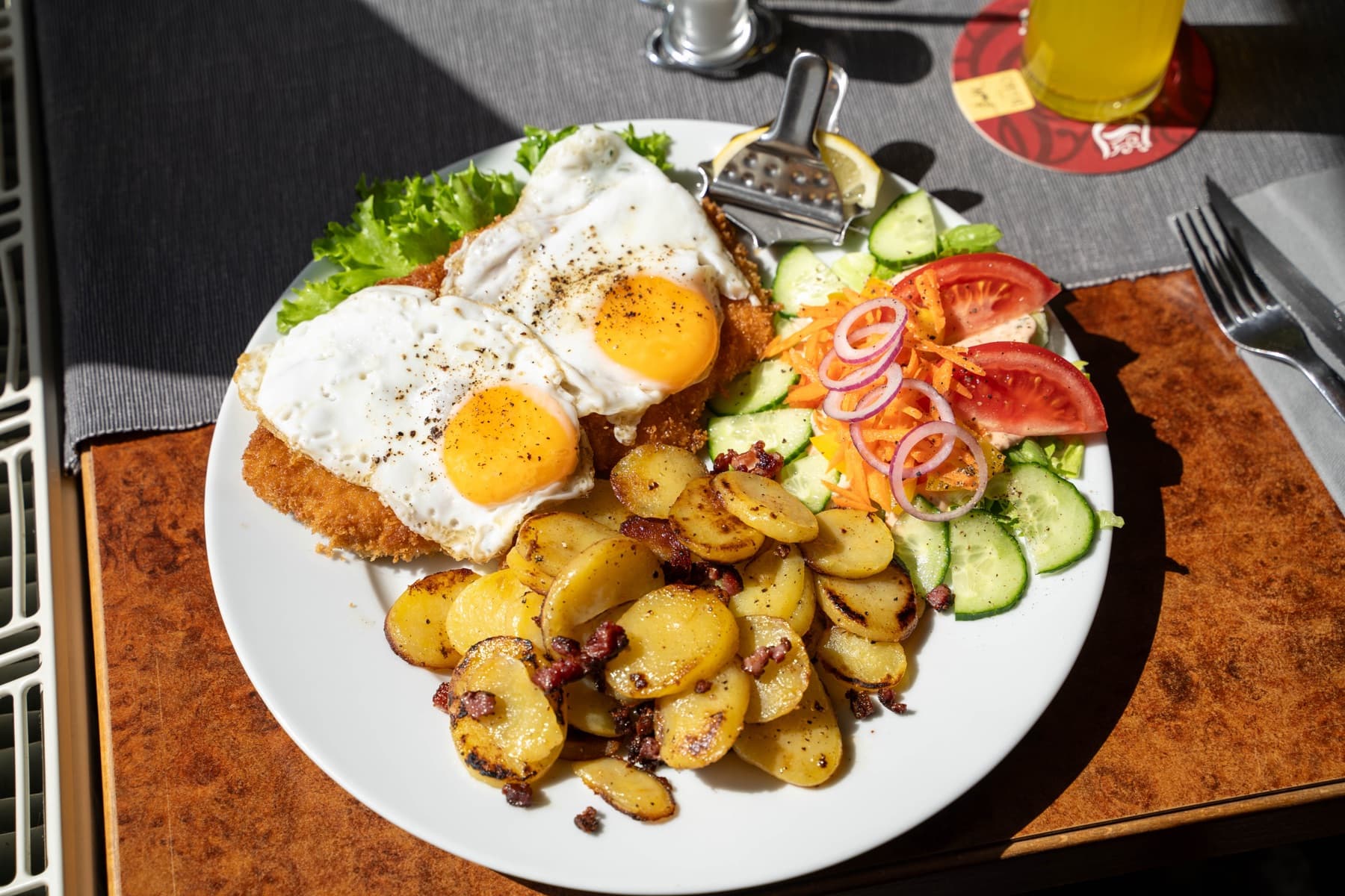 Schnitzel mit zwei Spiegeleiern, Bratkartoffeln und Salat